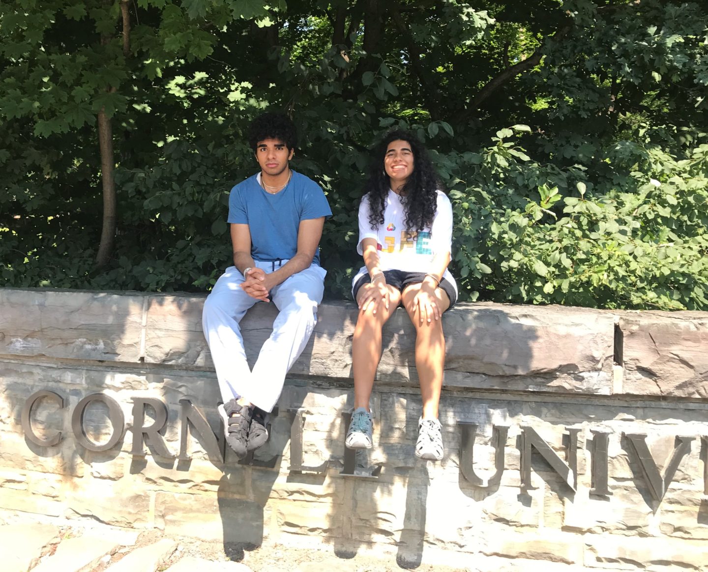 Eeshan and Vini Tripathii sitting on a wall at Cornell University.