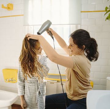 una mujer le seca el pelo a una niña en un cuarto de baño